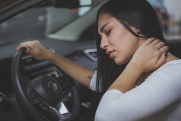 Personal Injury Protection (PIP) Insurance - Young Woman Rubbing Her Neck and Feeling Sore After Whiplash in a Car Crash